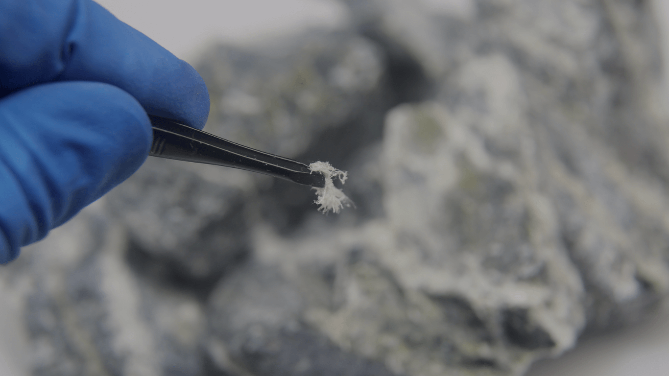 Asbestos fiber identification and testing: A close-up of suspected asbestos-containing material (ACM) being sampled for laboratory analysis.