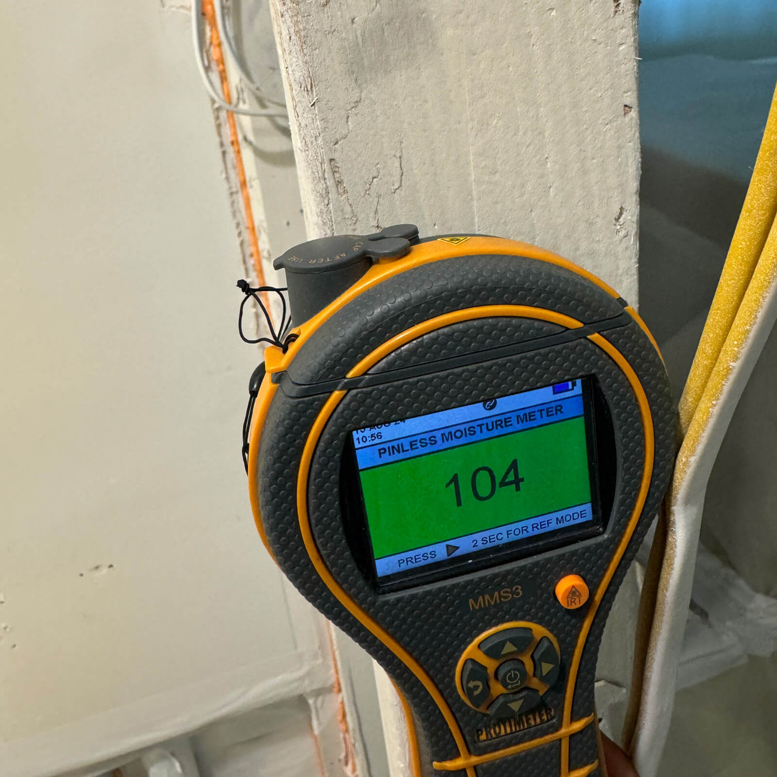 Vert Environmental specialist taking a pinless moisture meter reading on a wall.