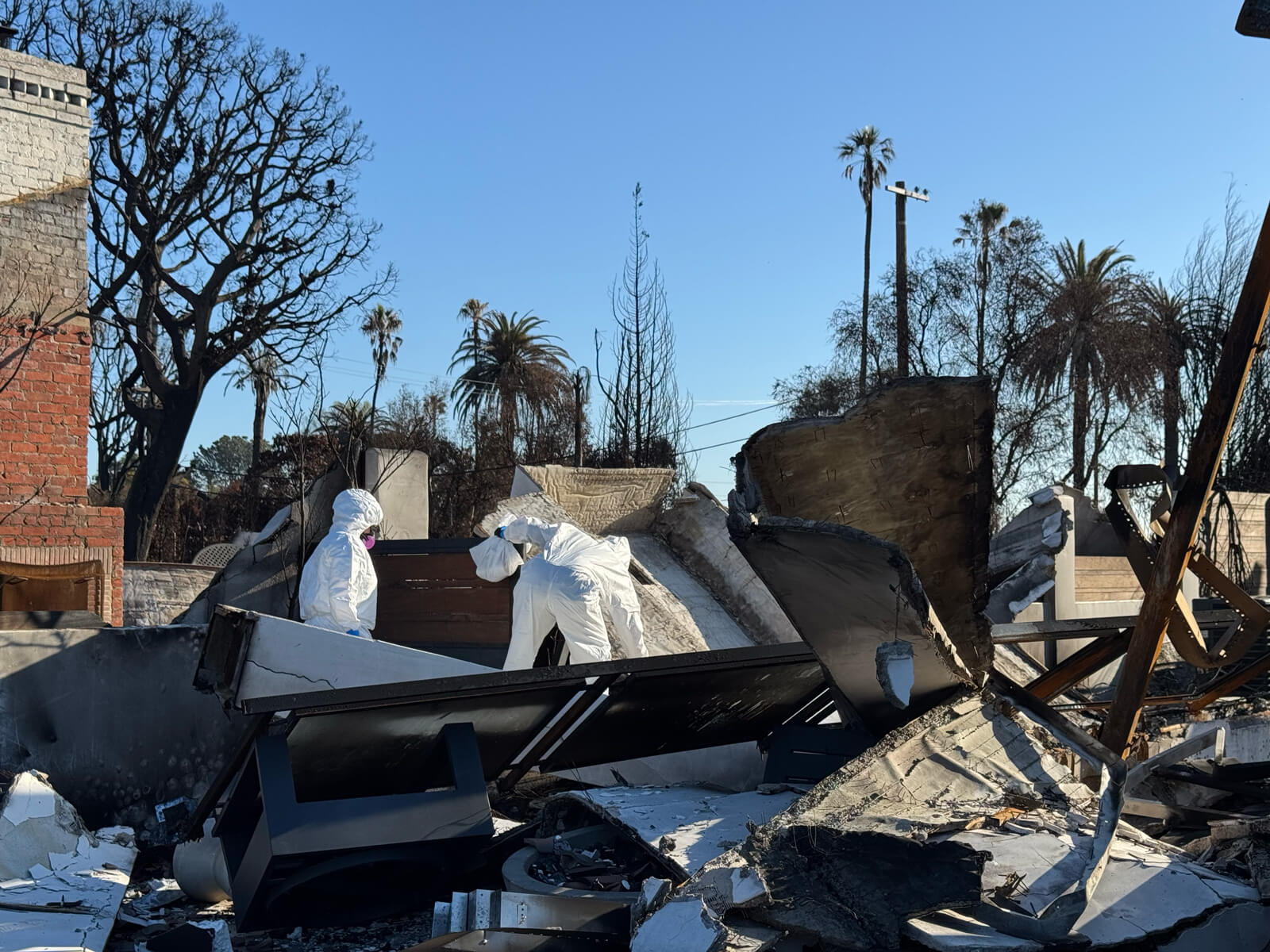 Vert Environmental specialists in protective gear conducting an environmental assessment at a fire-damaged property.